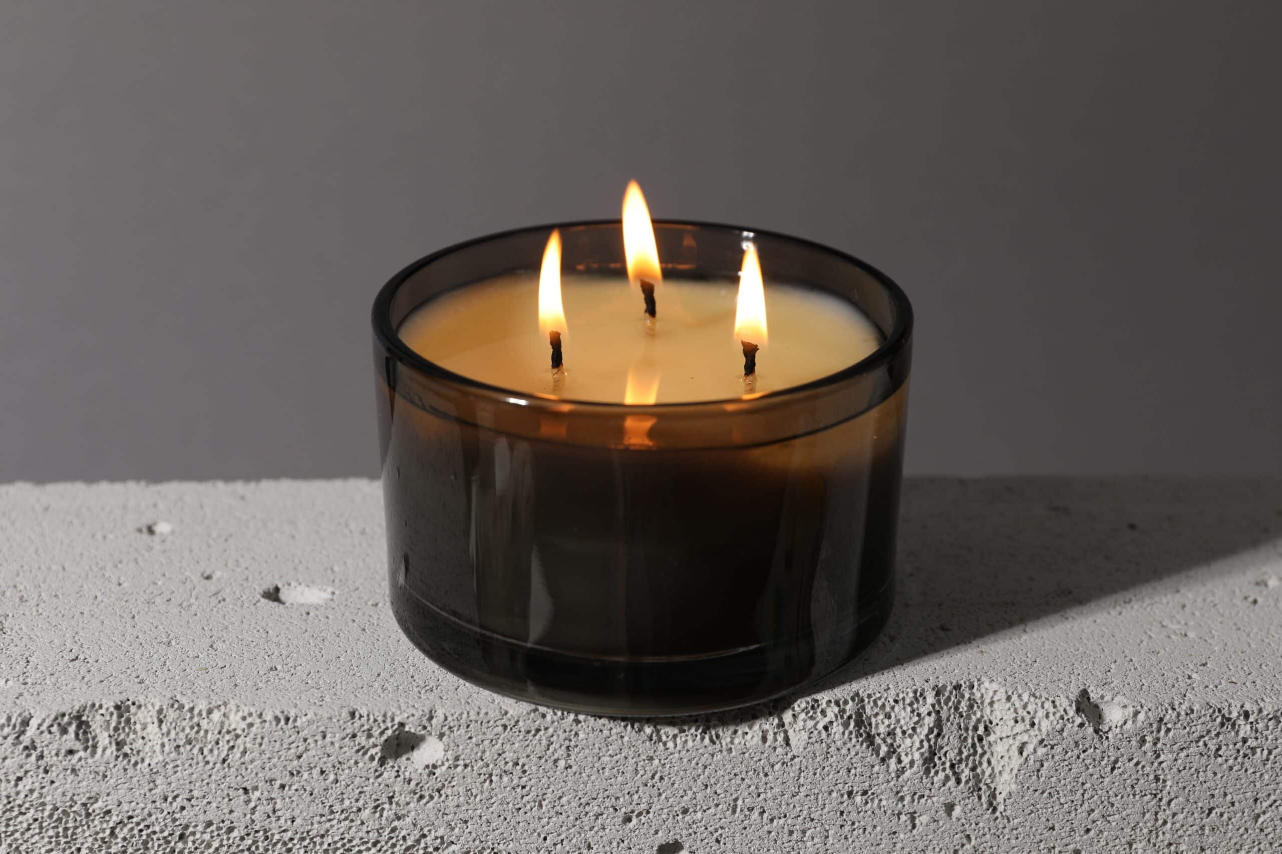 Burning,Soy,Wax,Candle,On,Concrete,Block,Against,Gray,Background,